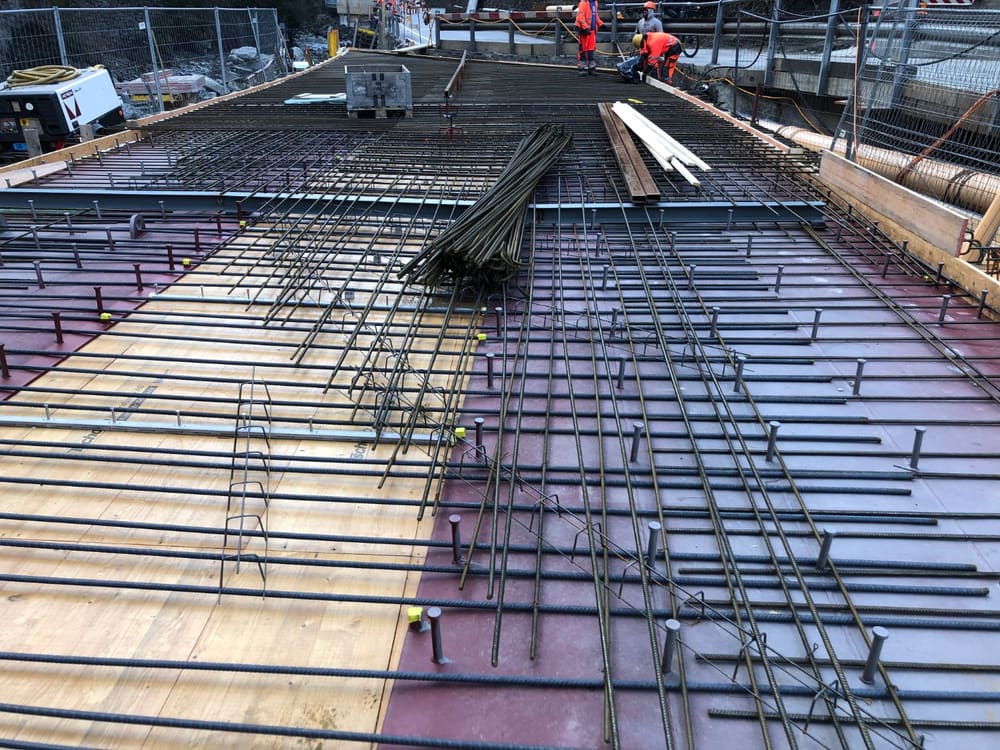 Bewehrung der Brückenplatte auf den zwei Hohlkastenträgern mit Kopfbolzendübeln, im Hintergrund Baustelle und Absperrungen